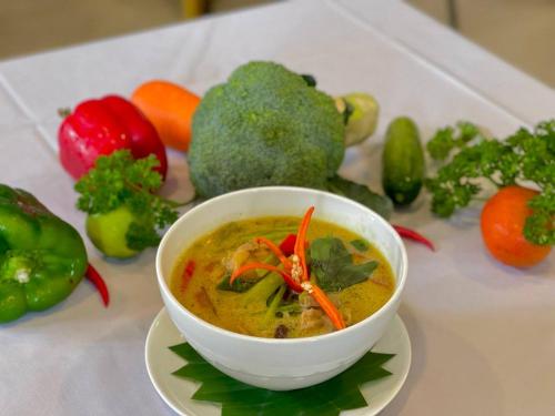 a bowl of soup on a white plate with vegetables at Homewood Hotel By Seuya Hotel in Siem Reap