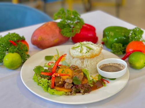 a plate of food with rice and vegetables on a table at Homewood Hotel By Seuya Hotel in Siem Reap