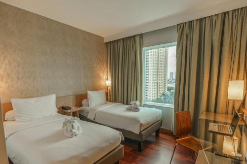 Rúm í herbergi á Hotel KIMAYA Slipi Jakarta By HARRIS