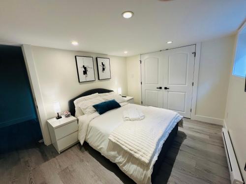 a bedroom with a white bed and a nightstand with a bed sidx sidx sidx at Quiet Basement Suite Steps from Quilchena Park in Vancouver in Vancouver
