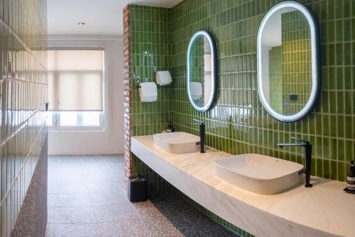 a green tiled bathroom with two sinks and mirrors at Santisookmidtown Pattani in Kampong Rusamileh