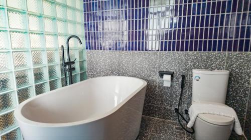 a bathroom with a bath tub and a toilet at Santisookmidtown Pattani in Kampong Rusamileh