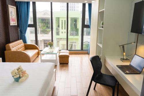 a room with a bed and a desk with a laptop at BRIO Hotels & Apartments in Da Nang