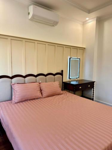 a bedroom with a pink bed with a desk and a television at CONIHOUSE - Homestay & Villa in Thôn Lại Thê