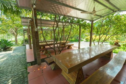 a patio with wooden benches and a ceiling fan at HDT Farm Stay Thanh Chuong in Thái Nhã