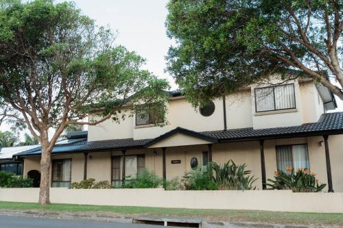 a large white house with trees in front of it at Sunny Dayz Shellharbour in Barrack Point