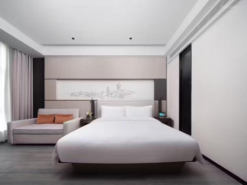 a bedroom with a large white bed and a couch at UrCove by HYATT Aksu in Aksu