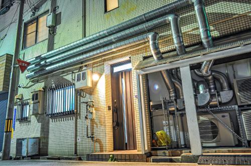 a building with pipes on the side of it at 最大19人一棟貸切4Bed rooms福島 in Osaka