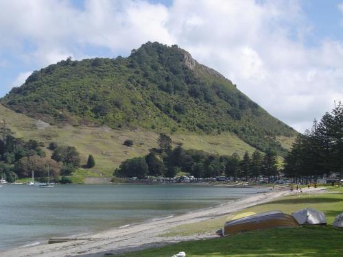 a mountain next to a body of water with tents at Seagulls Guesthouse in Mount Maunganui