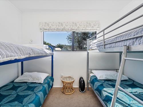 two bunk beds in a room with a window at Beaumont Beach Retreat - Pauanui Holiday Home in Pauanui