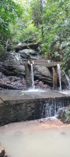 a stone bench sitting in front of a waterfall at Charming dark lodge in river in Weligama