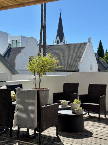 a patio with chairs and a table with a potted tree at Tuishuisie in Stellenbosch