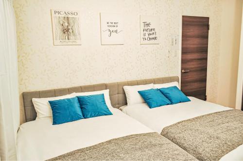 two beds with blue pillows in a bedroom at 最大19人一棟貸切4Bed rooms福島 in Osaka