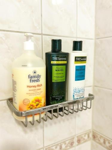a bathroom shelf with three bottles of soap and shampoo at Lovely 1-bedroom apartment with patio and sauna in Tampere
