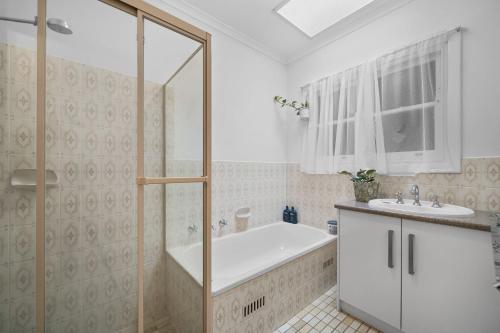 a bathroom with a tub and a sink at Glenelg Hideaway Bliss in Glenelg