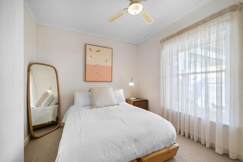 a white bedroom with a mirror and a bed at Glenelg Hideaway Bliss in Glenelg