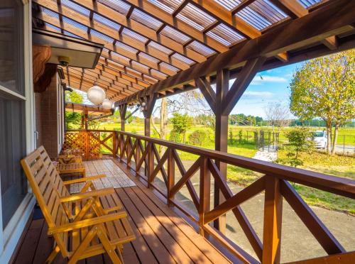 a porch with a wooden bench and a wooden pergola at Elle's Garden House in Nasushiobara
