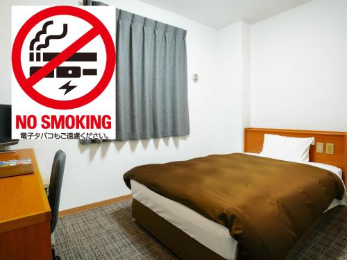 a bedroom with a no smoking sign next to a bed at Kumamoto Ichibamae Business Kurenai Hotel in Kumamoto