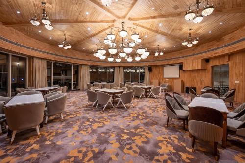 a conference room with tables and chairs and a screen at Royalpine Rosastays Kasauli in Kasauli
