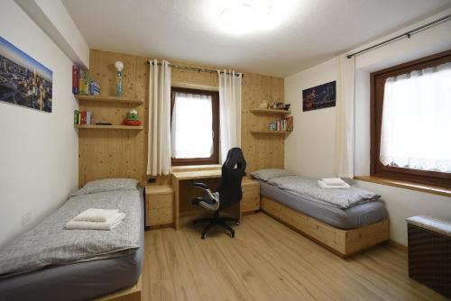 a bedroom with two beds and a desk and a chair at Appartamento Fontanive in Masarè