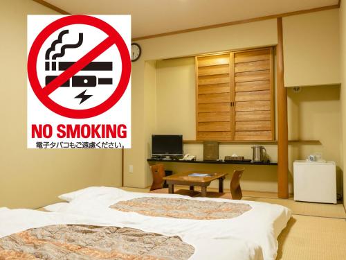a no smoking sign in a bedroom with a bed at Kumamoto Ichibamae Business Kurenai Hotel in Kumamoto