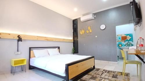 a bedroom with a bed and a table and a desk at Kenewae Living Near Alun-alun Wonosari Mitra RedDoorz in Wonosari