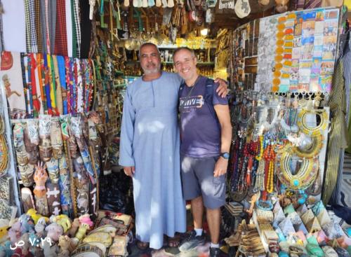two men standing in front of a store withpiredermottermottermottermott at Osiris Guest House in Abu Simbel