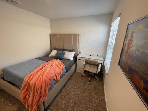 a small bedroom with a bed and a desk at Spacious 4-Bedroom Retreat with High-Speed WiFi and Tranquil Ambiance in Aubrey