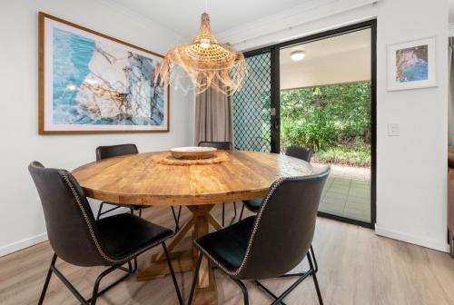 a dining room table with chairs and a chandelier at Modern & Stylish 2 Bedroom Townhouse in Noosaville