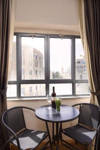a table with a bottle of wine and two chairs in front of a window at Mamilla view URBAN - Boutique hotel in Jerusalem