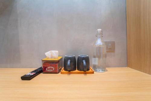 a remote control and a bottle on a table at Keenan Living Luxe Seturan in Seturan