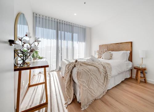 una camera bianca con un letto e una grande finestra di Spacious 1-Bed Apartment with Gym, BBQ & Parking a Kingston 