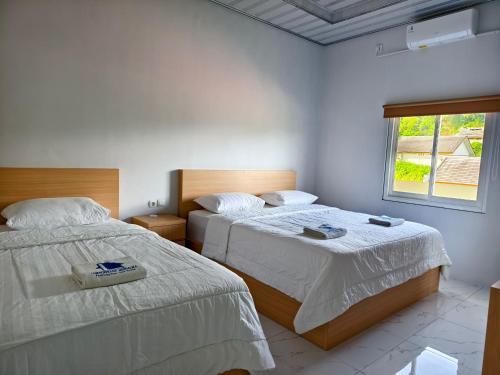 a bedroom with two beds and a window at Lombokhouse Mandalika in Kuta Lombok