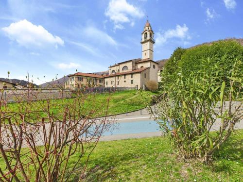 a building with a clock tower in the middle of a field at Loggia di charme in Malcantone in Curio