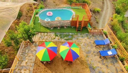 an overhead view of two colorful umbrellas next to a pool at Orchard Green Dummi in Nāldera