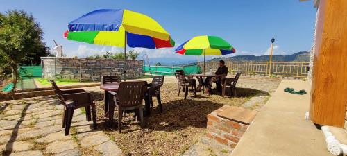 a man sitting at a table under two umbrellas at Orchard Green Dummi in Nāldera