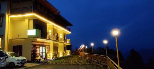 a building with a car parked outside of it at night at Orchard Green Dummi in Nāldera