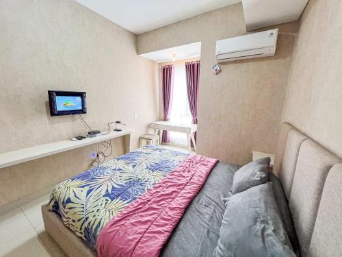 a bedroom with a bed and a tv on the wall at Barsa City Babarsari 266 in Yogyakarta