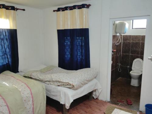 a bedroom with two twin beds and a toilet at Kings jungle safari & Culture home stay in Meghauli