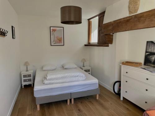 - une chambre dotée d'un lit avec des draps blancs dans l'établissement Petit gîte - Ty Bihan, à Querrien