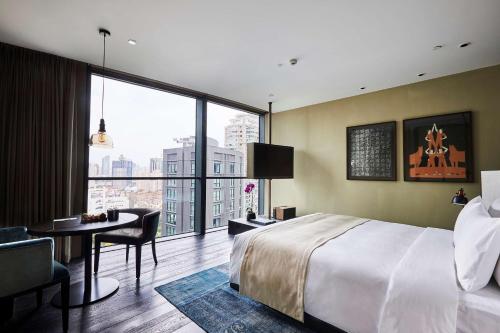a bedroom with a bed and a desk and a large window at The Middle House in Shanghai