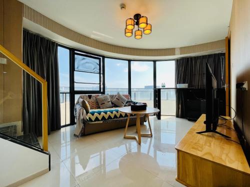 a living room with a couch and a tv and a table at Poly Central Plaza By Boli at Sanya City Center#Near Joy City in Sanya