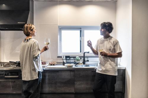 two people standing in a kitchen holding glasses of wine at BORO SAUNA Sapporo in Sapporo