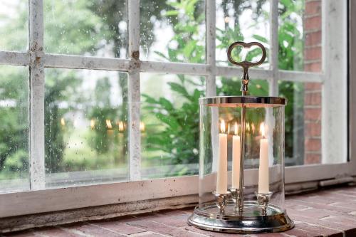 a candle with a heart in a glass container on a window at Hotel Alte Werft in Papenburg