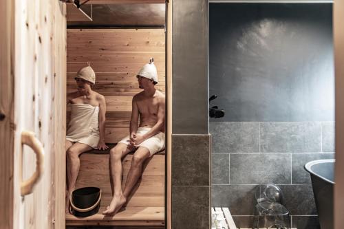 two men sitting in a sauna in a bathroom at BORO SAUNA Sapporo in Sapporo