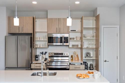 a kitchen with stainless steel appliances and wooden cabinets at Luxury Apartments by Hyatus Boston Somerville in Somerville