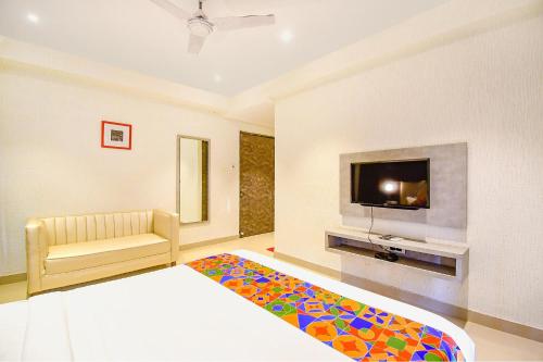 a room with a bed and a tv and a couch at FabHotel Lake View Topsia in Kolkata