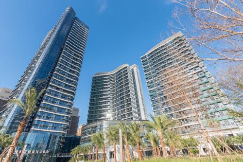 two tall buildings in a city with palm trees at Poly Central Plaza By Boli at Sanya City Center#Near Joy City in Sanya