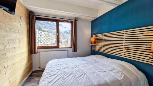 Cet appartement comprend une chambre dotée d'un lit avec un mur bleu et une fenêtre. dans l'établissement Résidence Betelgeuse - Appartement confortable · Proche des pistes et des commerces · Balcon MAE-7376, à Flaine