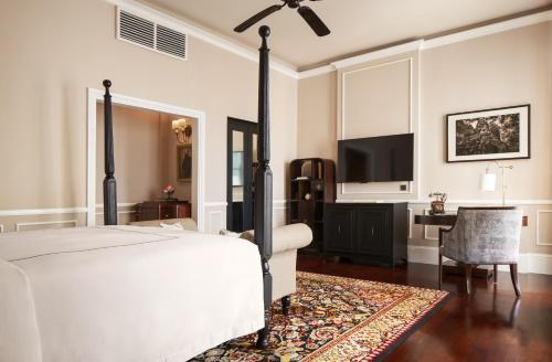 a bedroom with a bed and a flat screen tv at Raffles Grand Hotel d'Angkor in Siem Reap